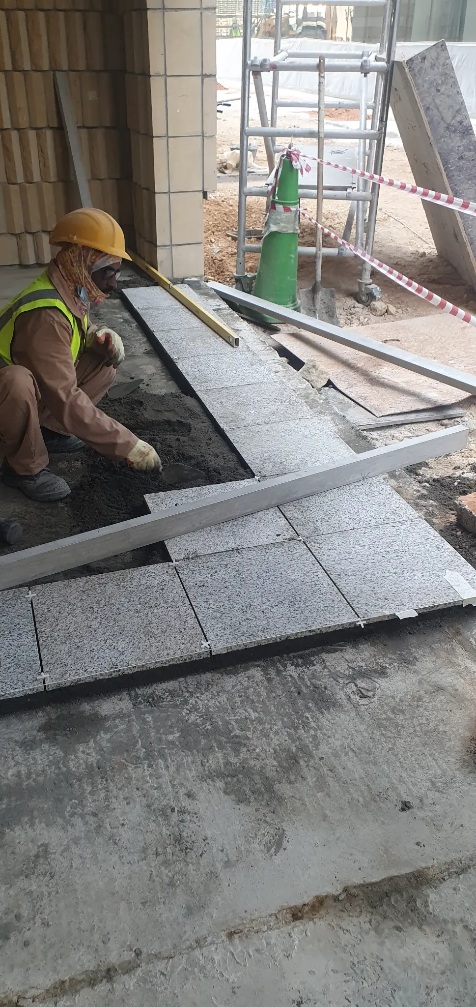 Worker installing granite floor tiles with level