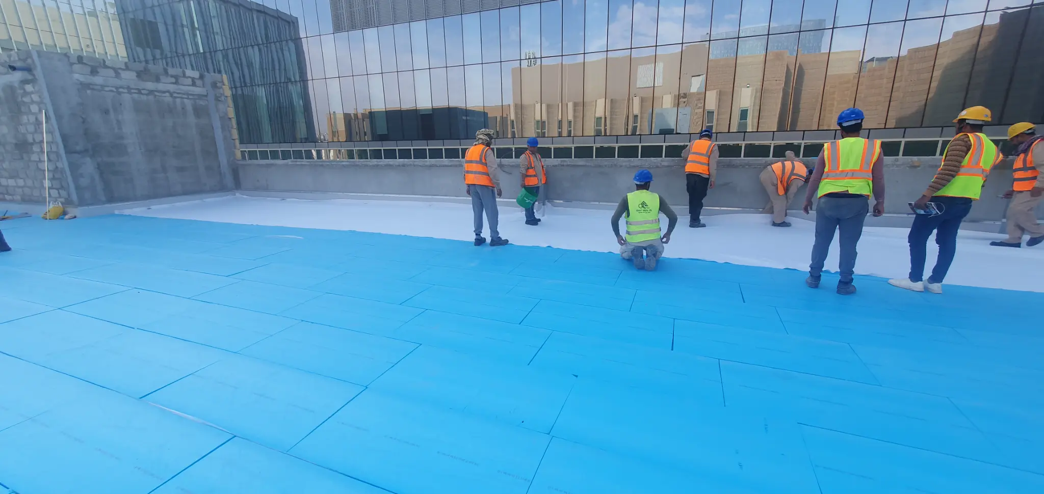 Crew applying waterproofing membrane on roof